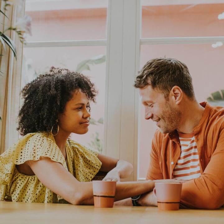 A couple sit discussing their financial planning over coffee.