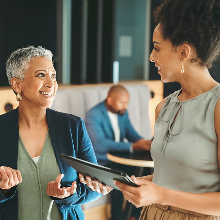 Two smartly dressed employees chat in their office